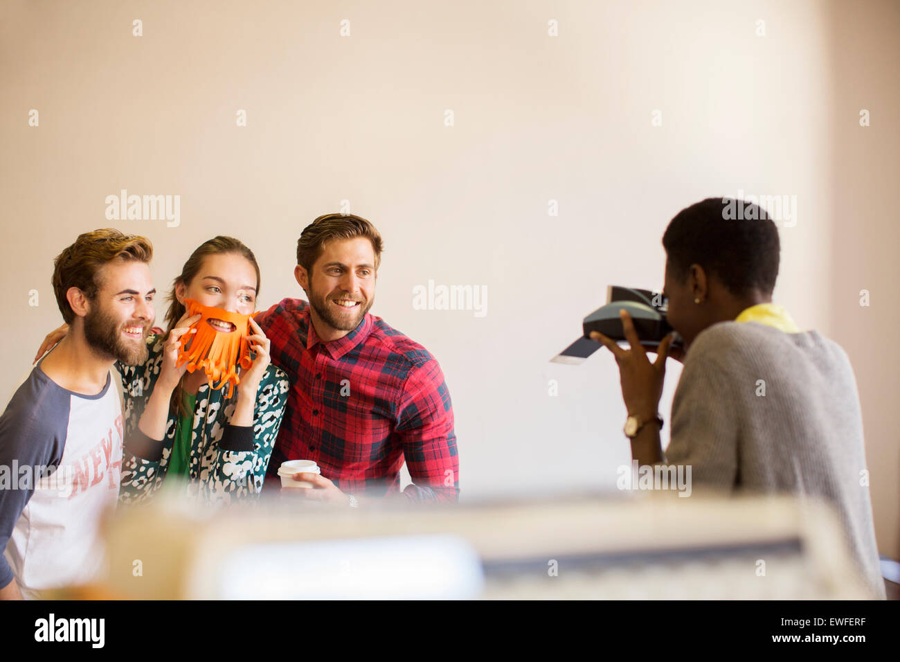 Kreative Geschäftsleute spielerisch posiert für Mitarbeiter mit Sofortbild-Kamera Stockfoto