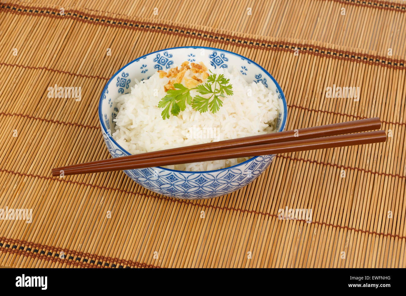 Schüssel Reis mit Stäbchen verziert mit gebratenen Zwiebeln und Koriander Stockfoto