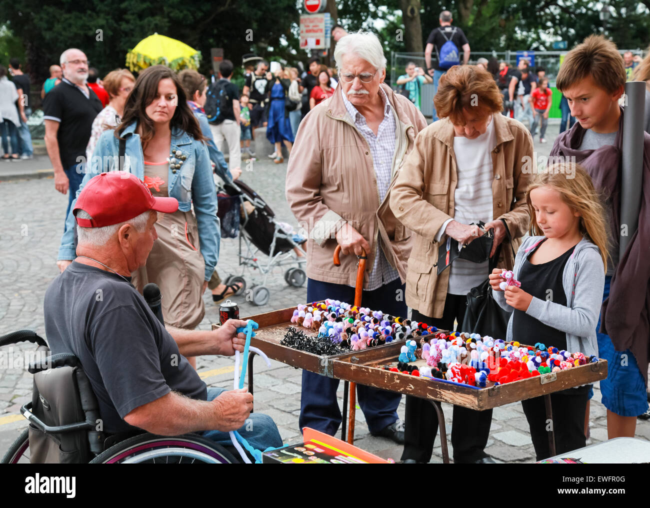 Paris, Frankreich - 9. August 2014: Behinderte ältere Mann kleine bunte Spielzeug schenken in der Nähe von Sacre Coeur Basilika in Sommertag Stockfoto