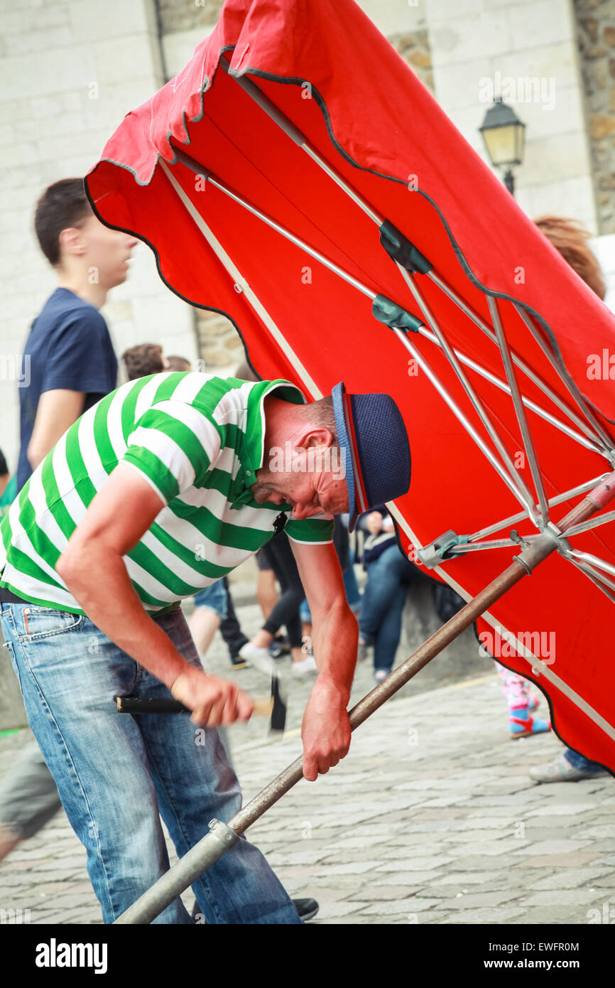Paris, Frankreich - 9. August 2014: Erwachsene zorniger Mann mit Hummer versucht, großen roten Regenschirm zu schließen Stockfoto