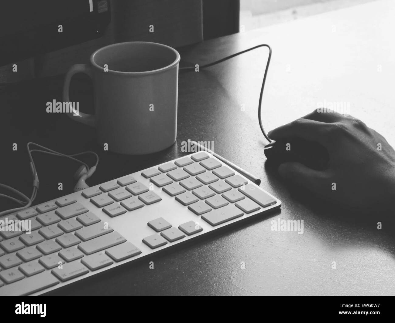 Hand mit der Maus am Schreibtisch mit Tastatur und Cup Stockfoto