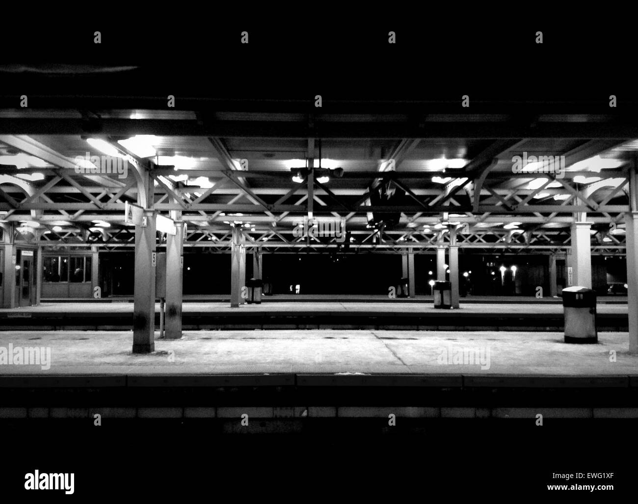 Ein minimalistisches Schwarz-weiß-Bild von U-Bahnhofslichtern mit einfachen Säulen und geometrischen Linien. Das Foto konzentriert sich auf den starken Kontrast zwischen Licht und Schatten und unterstreicht das klare, moderne Design der Station. Stockfoto