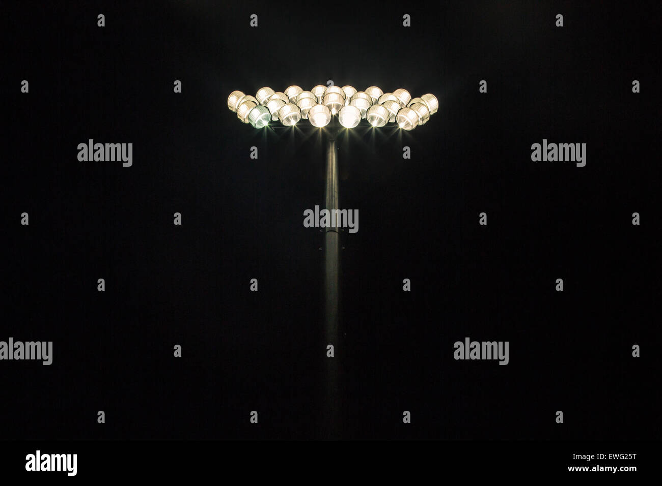 Ein helles Stadionlicht beleuchtet die dunkle Kulisse und strahlt ein starkes und intensives Leuchten aus. Die leistungsstarke Lichtquelle bildet einen Kontrast zum schwarzen Hintergrund und zeigt seine Helligkeit. Stockfoto
