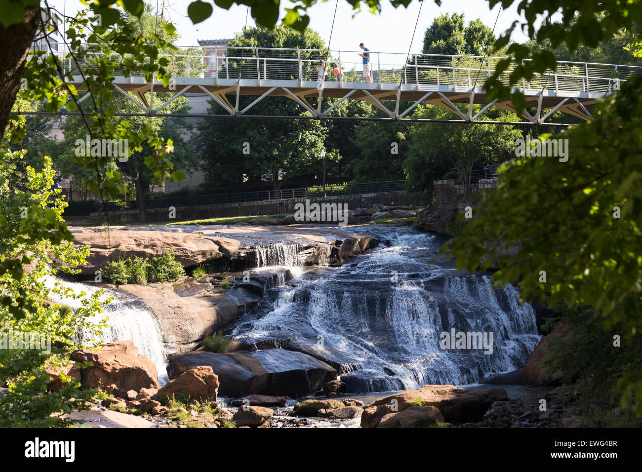 Die Brücke der Freiheit, eine gekrümmte Hängebrücke überquert die Reedy River Falls im schönen und aufregenden Zentrum von Greenville, SC. Stockfoto