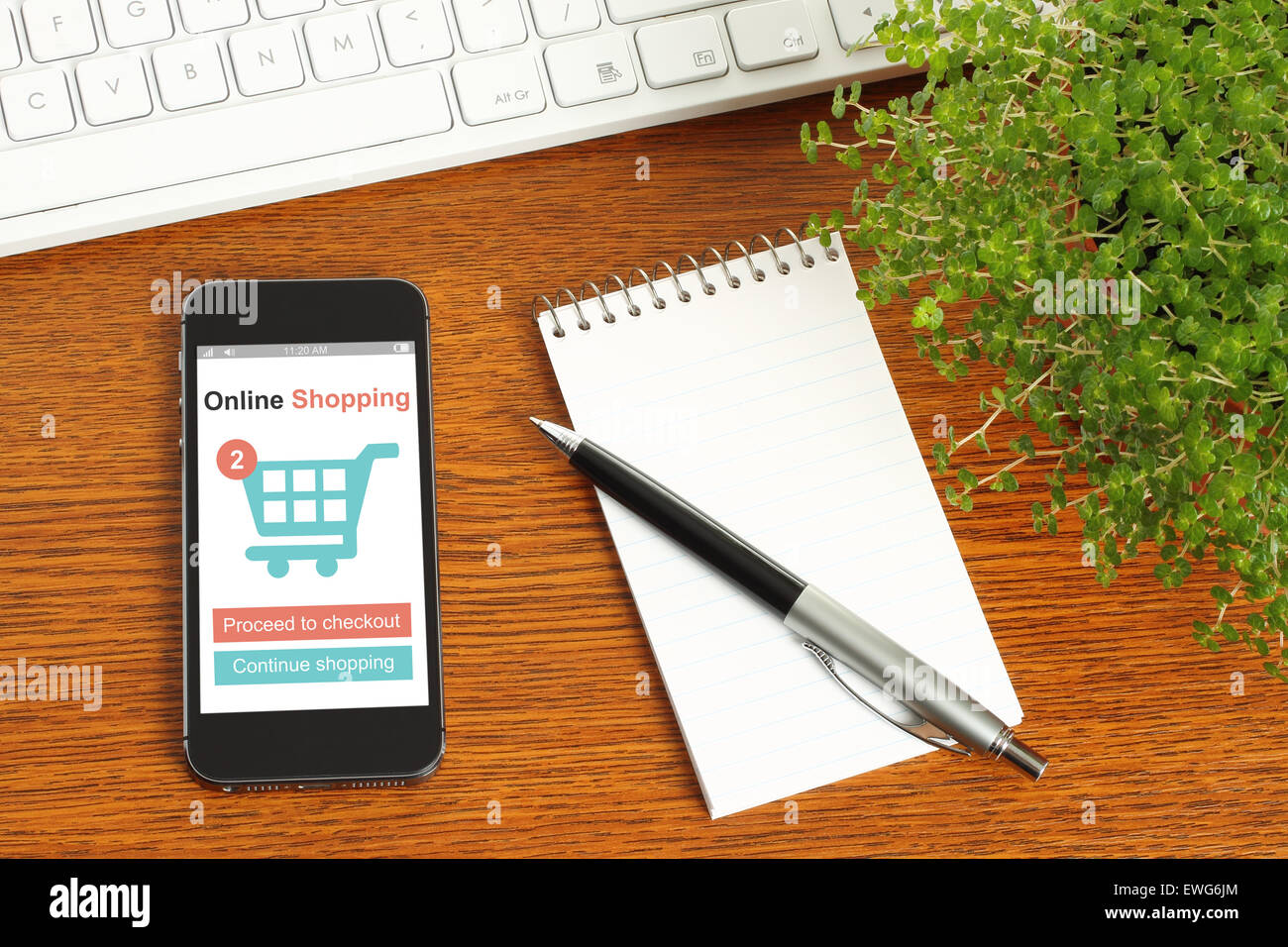 Smartphone mit Online-shopping-Konzept, Tastatur, Notizblock, Stift und Grünpflanze auf hölzernen Hintergrund Stockfoto