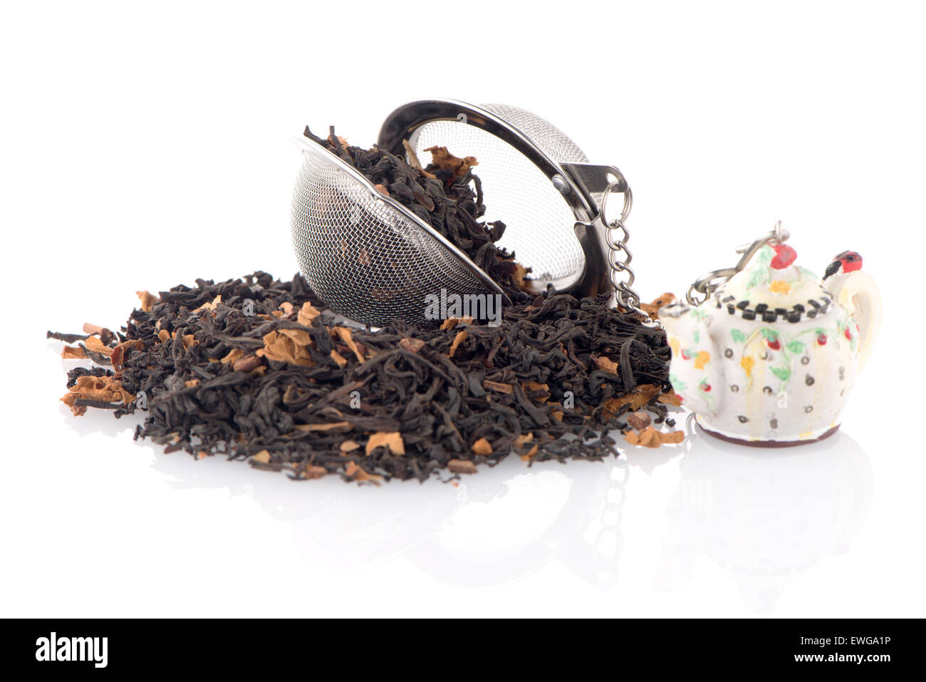 Aromatischer Schwarztee trocken mit Blütenblättern und ein Teesieb auf weißen reflektierenden Hintergrund. Stockfoto