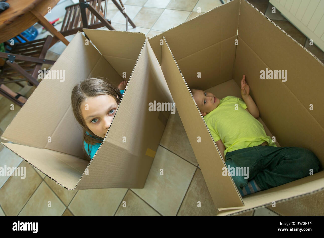 Kinder sitzen in Kartons. Kartons Auspacken und Umzug in ein neues Zuhause. Housewarming-Konzept. Stockfoto