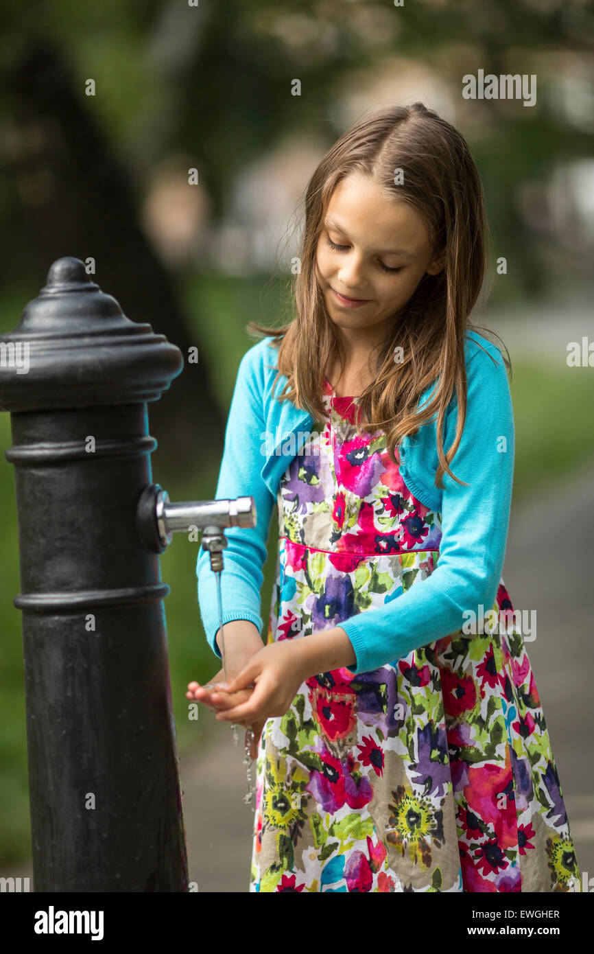 Kleine süße Mädchen wäscht Hände unter Wasser Handpumpe auf der Straße in der Altstadt. Stockfoto