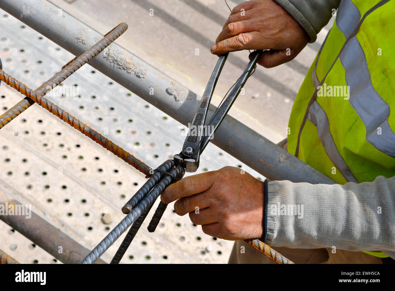 Arbeiter mit Zange und Draht, um Stahl, Betonstahl für armierten Beton zusammen zu binden gießen Stockfoto