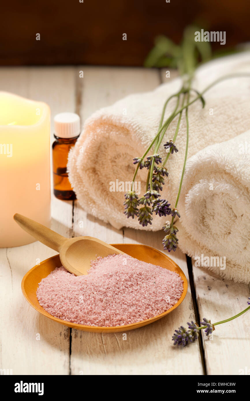 Spa-Stillleben mit Badesalz, Lavendelblüten, Kerze und Handtücher Stockfoto