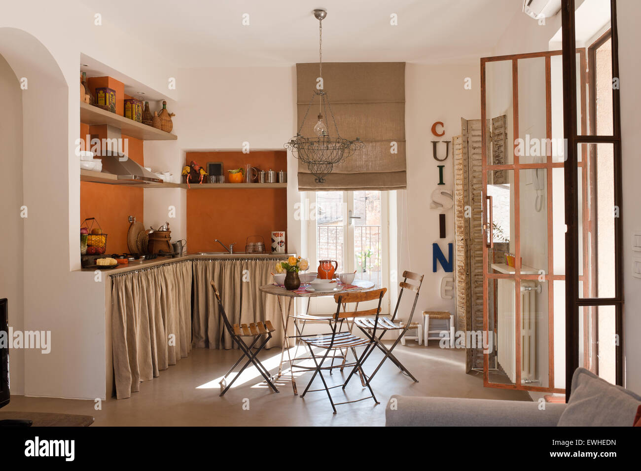 Café-Tisch und Stühle im Küchenbereich mit französischen Draht Kronleuchter und rustikalen Leinen Gardinen Stockfoto