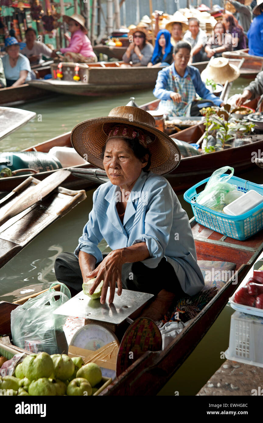 Voller Touristen Boote schwimmen hinter einem Thai Dame sitzt auf ihrem Boot in Damneon Saduak floating Markt außerhalb Bangkok Thailand Stockfoto