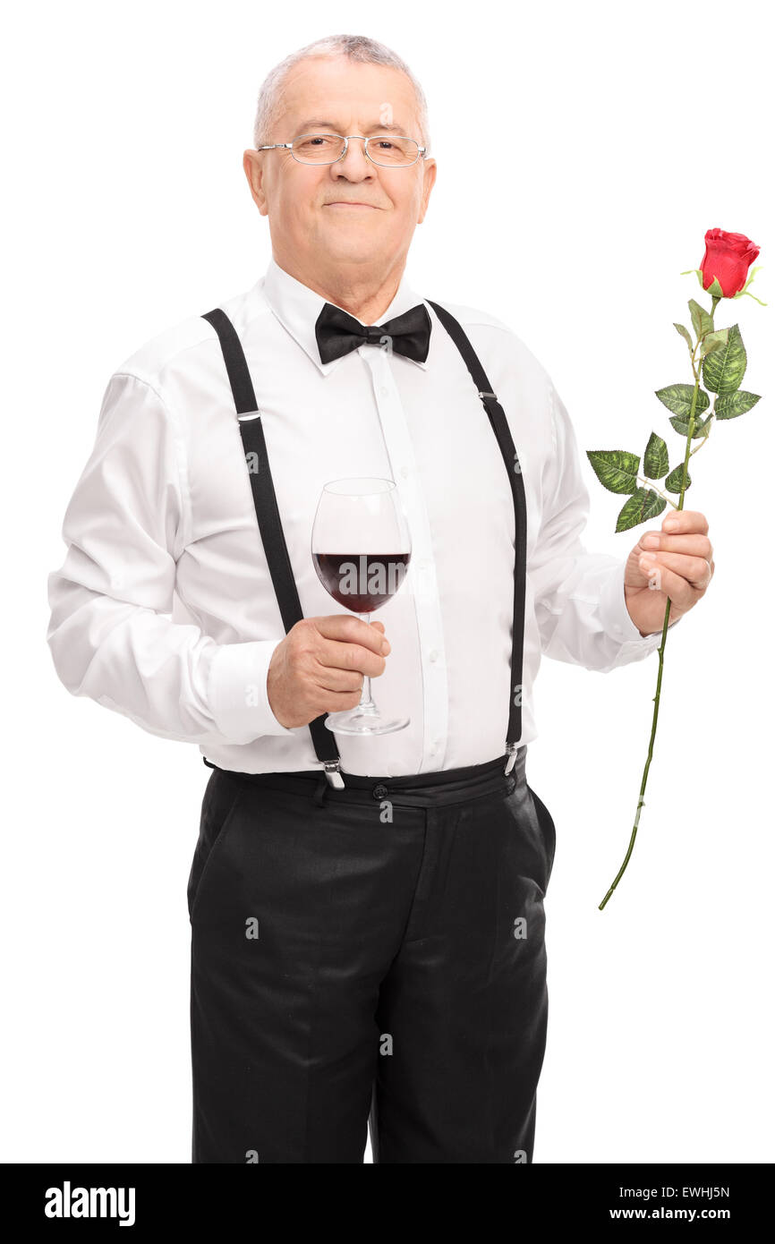 Vertikale Aufnahme eines romantischen senior Gentleman mit einem Glas Rotwein und eine rote Rose isoliert auf weißem Hintergrund Stockfoto
