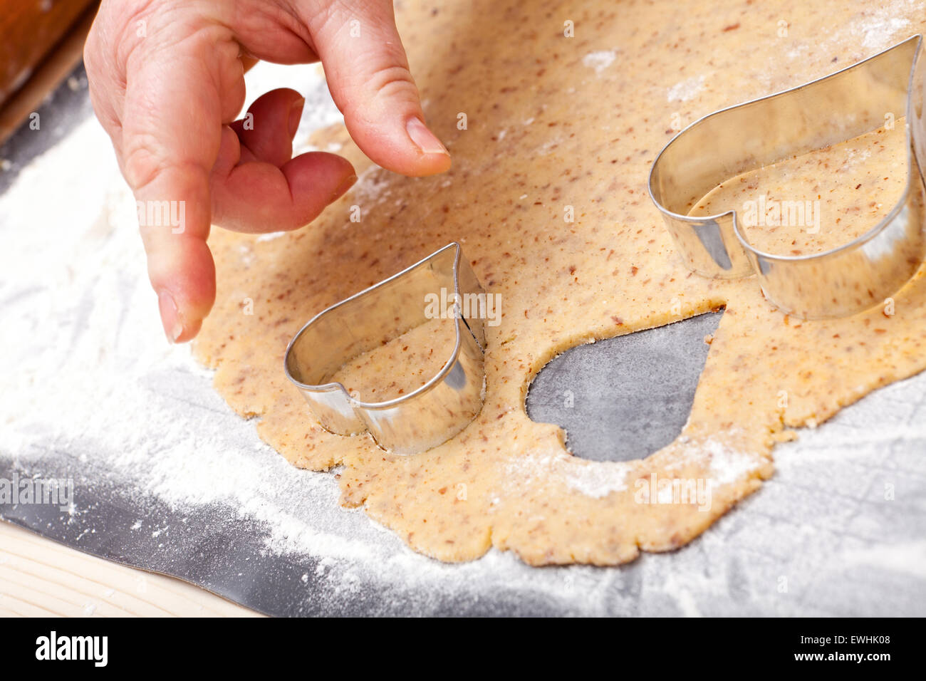 Schneiden Sie Cookies in Herzform mit Ausstecher aus frische Plätzchenteig Stockfoto