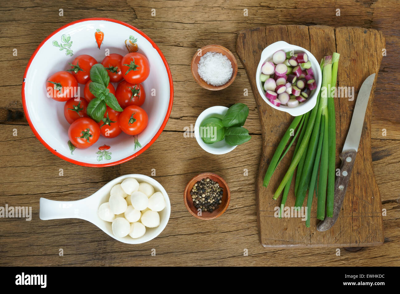 Zutaten für einen Tomatensalat auf einem rustikalen Holzbrett Stockfoto