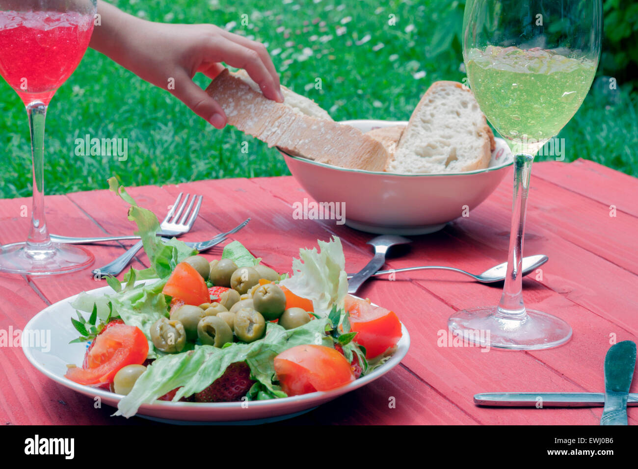 eine Sommer-Mahlzeit in einem Garten mit einer Hand ein Stück Brot Stockfoto