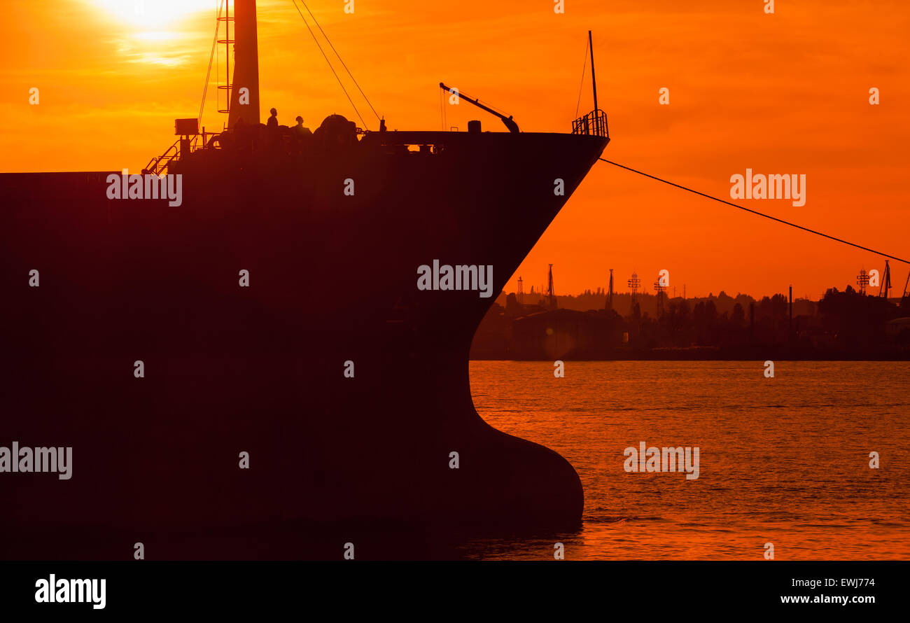Große industrielle Frachtschiff beugen Silhouette in hellen orange Sonnenuntergang Sonnenlicht, Hafen Varna, Bulgarien. Foto mit natürlichen Linse flar Stockfoto