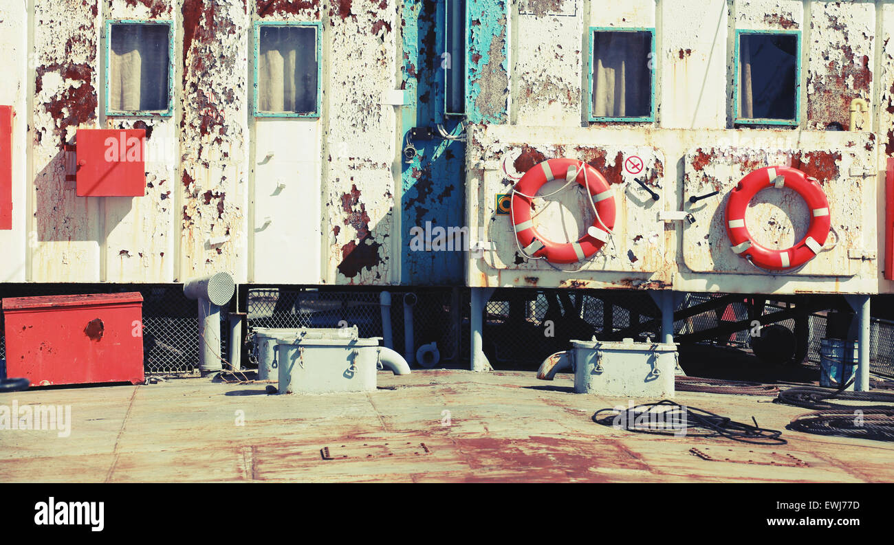 Handelsschiff verrostete weißen Aufbauten Stadtmauer mit Rettungsringen. Vintage Retro stilisierte Foto mit Tonwertkorrektur Filter, Stockfoto