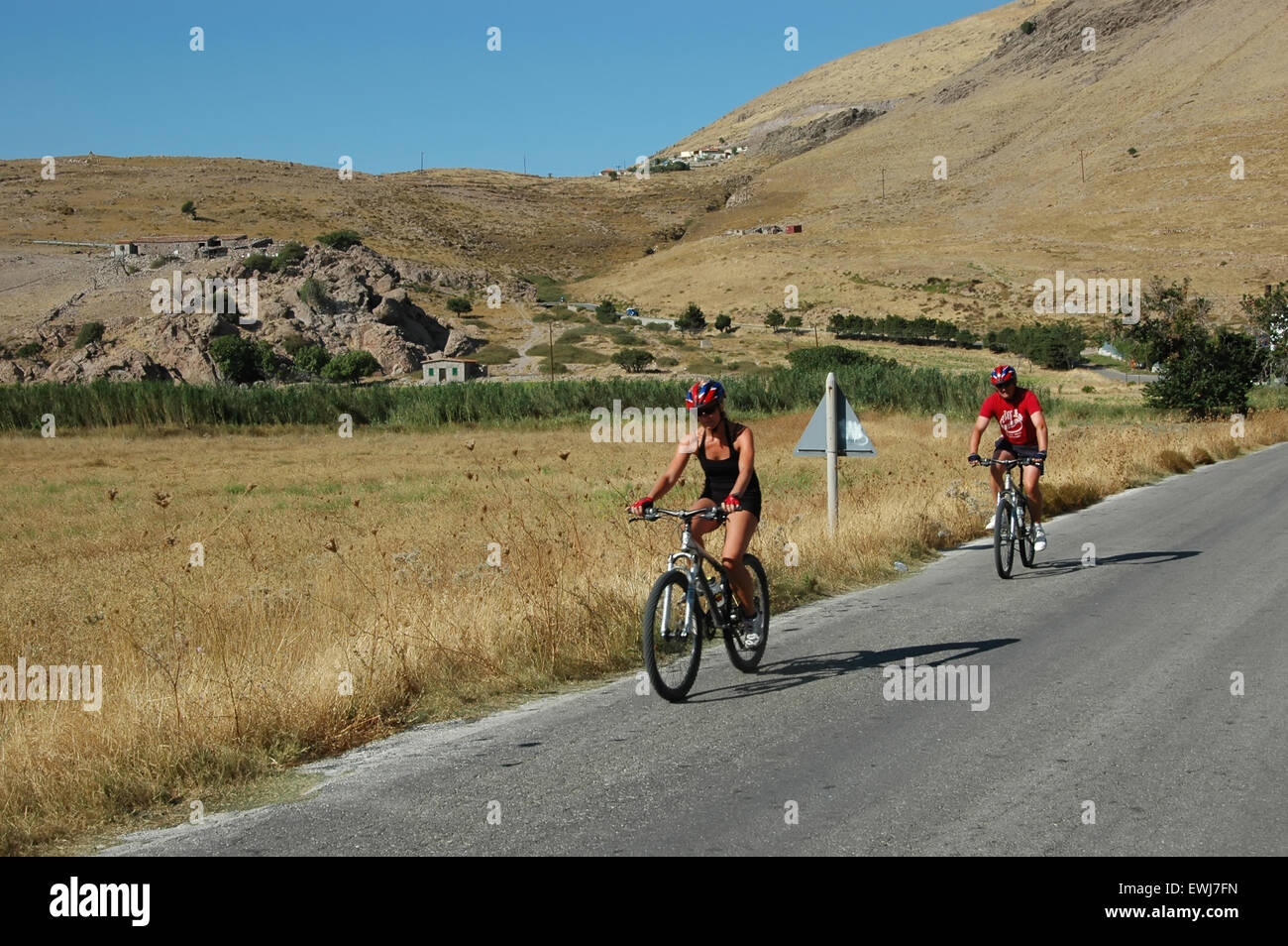 Britische Touristen Radfahren auf der Straße von Avlonas Bay Blick auf die umliegende Landschaft. Lemnos oder Limnos Insel Griechenlands. Stockfoto