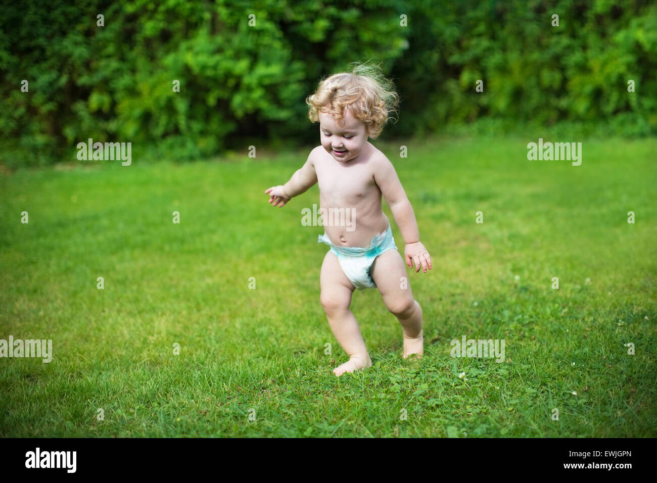 Lustige kleine Baby tragen eine Windel an einem heißen Sommertag im Garten laufen Stockfoto