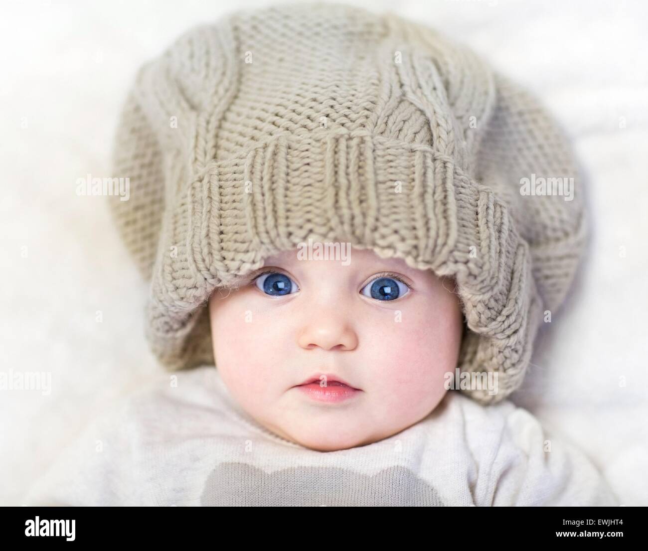 Entzückende Neugeborene Baby tragen eine große Mütze und ein warmer  Pullover entspannend auf einer weißen Decke Stockfotografie - Alamy