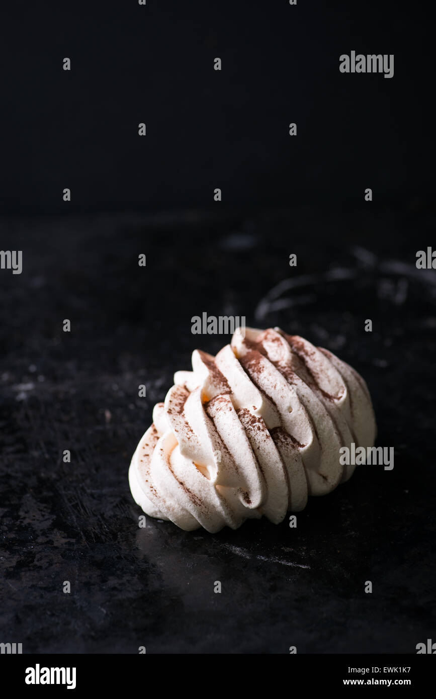 Baiser mit Kakaopulver auf dunklem Hintergrund, Tiefenschärfe, kopieren Raum Stockfoto