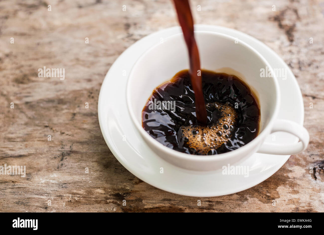 Kaffee-Spritzer in einer Tasse Kaffee. Auf einem hölzernen Hintergrund Stockfoto