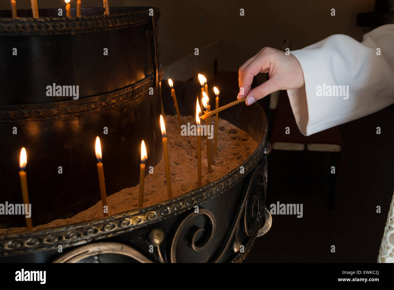 Frau Hand Anzünden von Kerzen in der Kirche Stockfoto