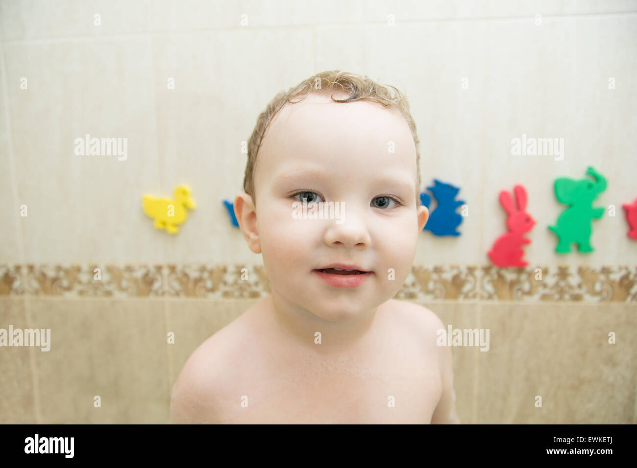 Porträt eines Babys in einem Badezimmer mit farbigen Spielzeug im Hintergrund Stockfoto