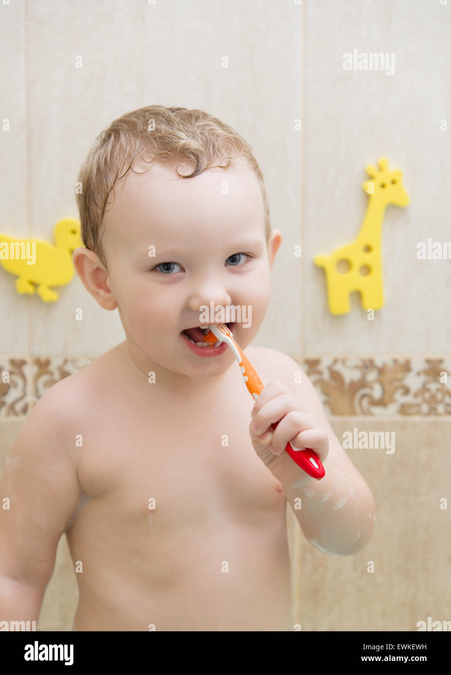 Porträt eines Babys in einem Badezimmer mit farbigen Spielzeug im Hintergrund Stockfoto