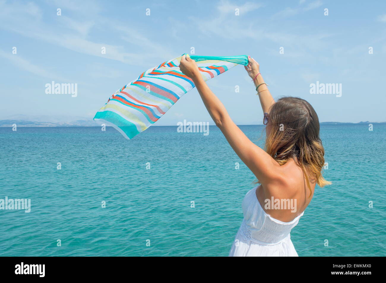 Mädchen im weißen Kleid winken einen bunten Schal am Meer Stockfoto