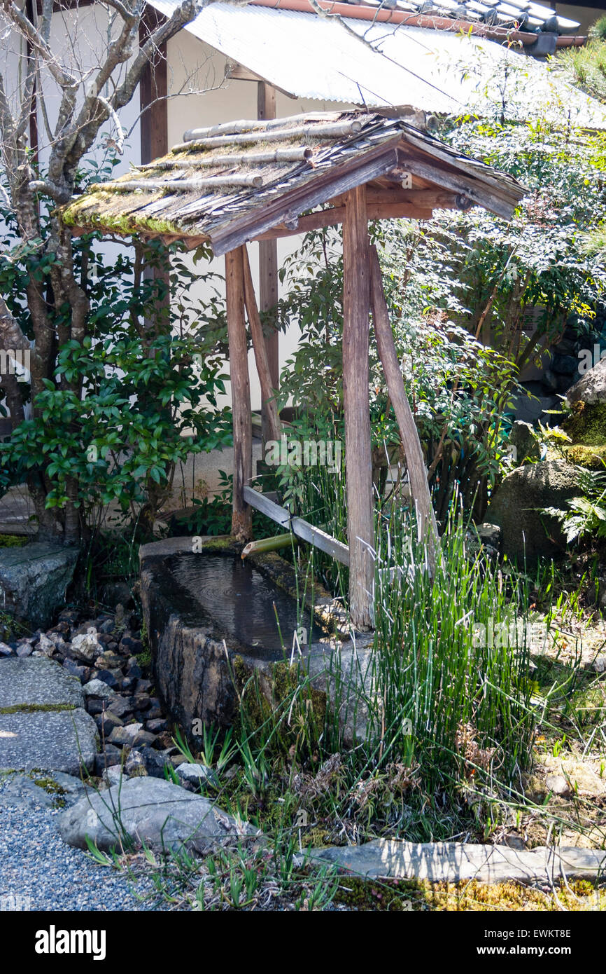 Becken aus Stein mit Bambus Wasserpfeife unter hölzernen Rahmen, Unterstützung der kleinen Dach. Eine Temizuya chozuya, auch genannt, der Tempel oder Schrein Reinigung Becken. Stockfoto