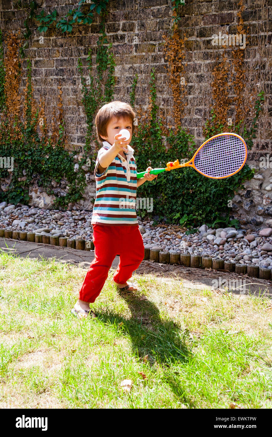 Kaukasier Kind, Junge, 4-5 Jahre alt, im Garten, das Tragen von T-Shirt und  Hose, mit einem Kunststoff Tennis Schläger und Ball Tennis spielen auf dem  Rasen Stockfotografie - Alamy