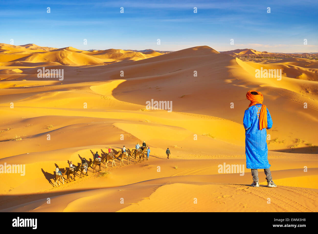 Berber Mann Blick auf Kamel-Karawane, Erg Chebbi Wüste bei Merzouga, Sahara, Marokko Stockfoto