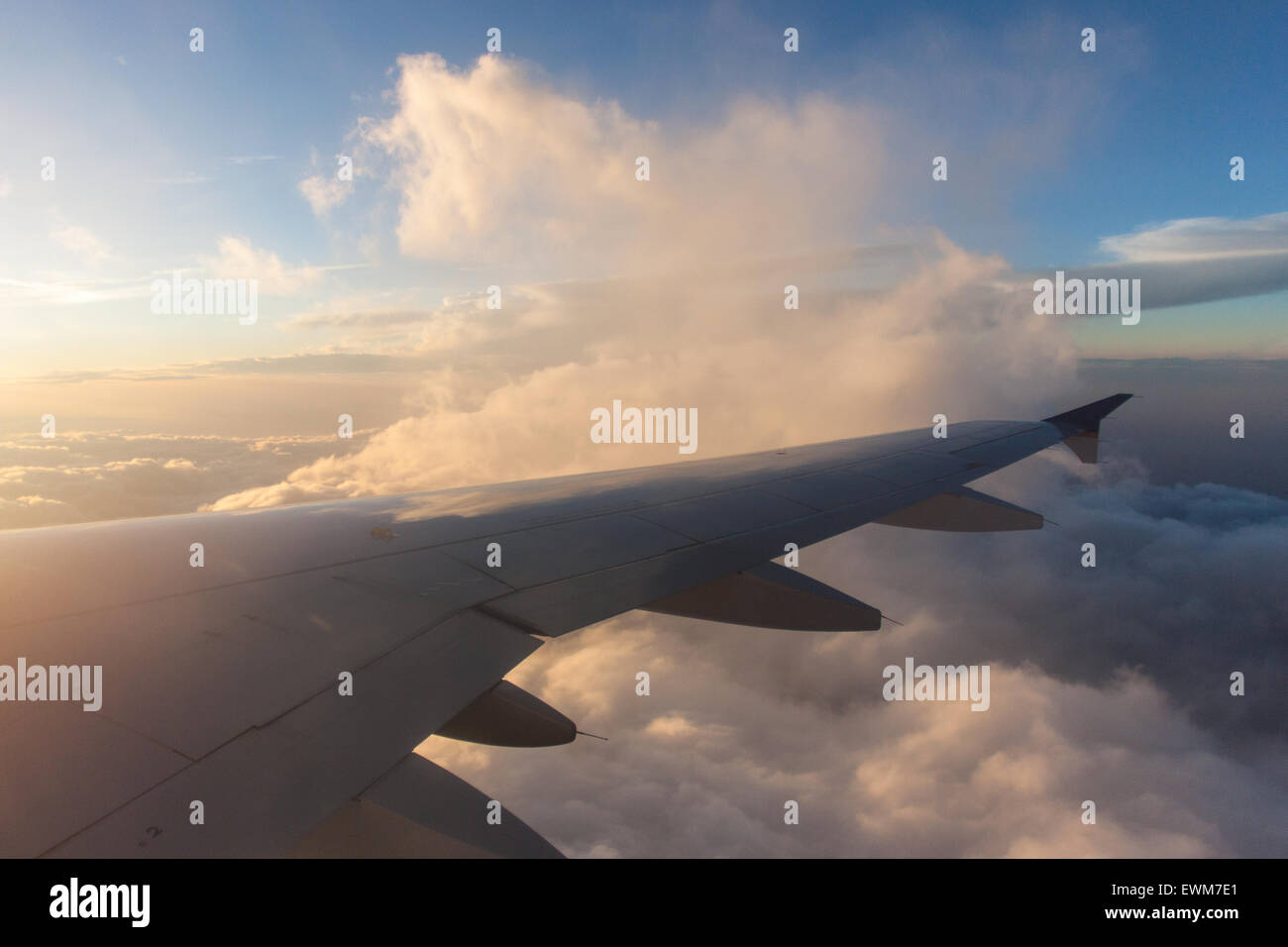 Die Sonne beleuchtet Wolken in der Nähe von einem Flugzeugflügel. Stockfoto