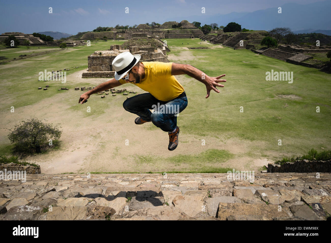 Hispanic Mann springt in die Luft über die steinernen Stufen von Monte Alban Ruinen in Mexiko Stockfoto