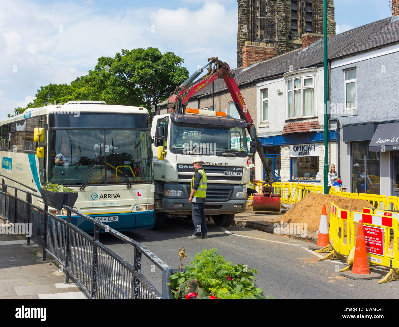 Ein Bus, geführt durch einen schmalen Spalt während Straße verengt für Gasleitung Ersatz im Dorfzentrum Marske arbeitet Stockfoto