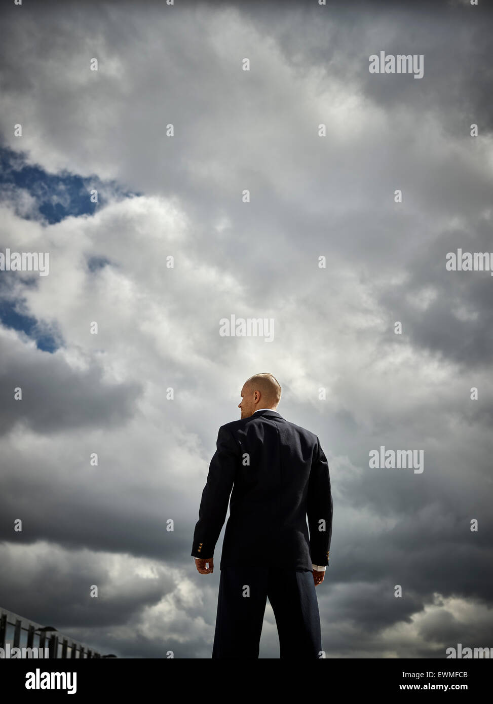 Rückseite ein gut aussehender Mann und er trägt einen dunklen Anzug, Himmel und Wolken im Hintergrund Stockfoto
