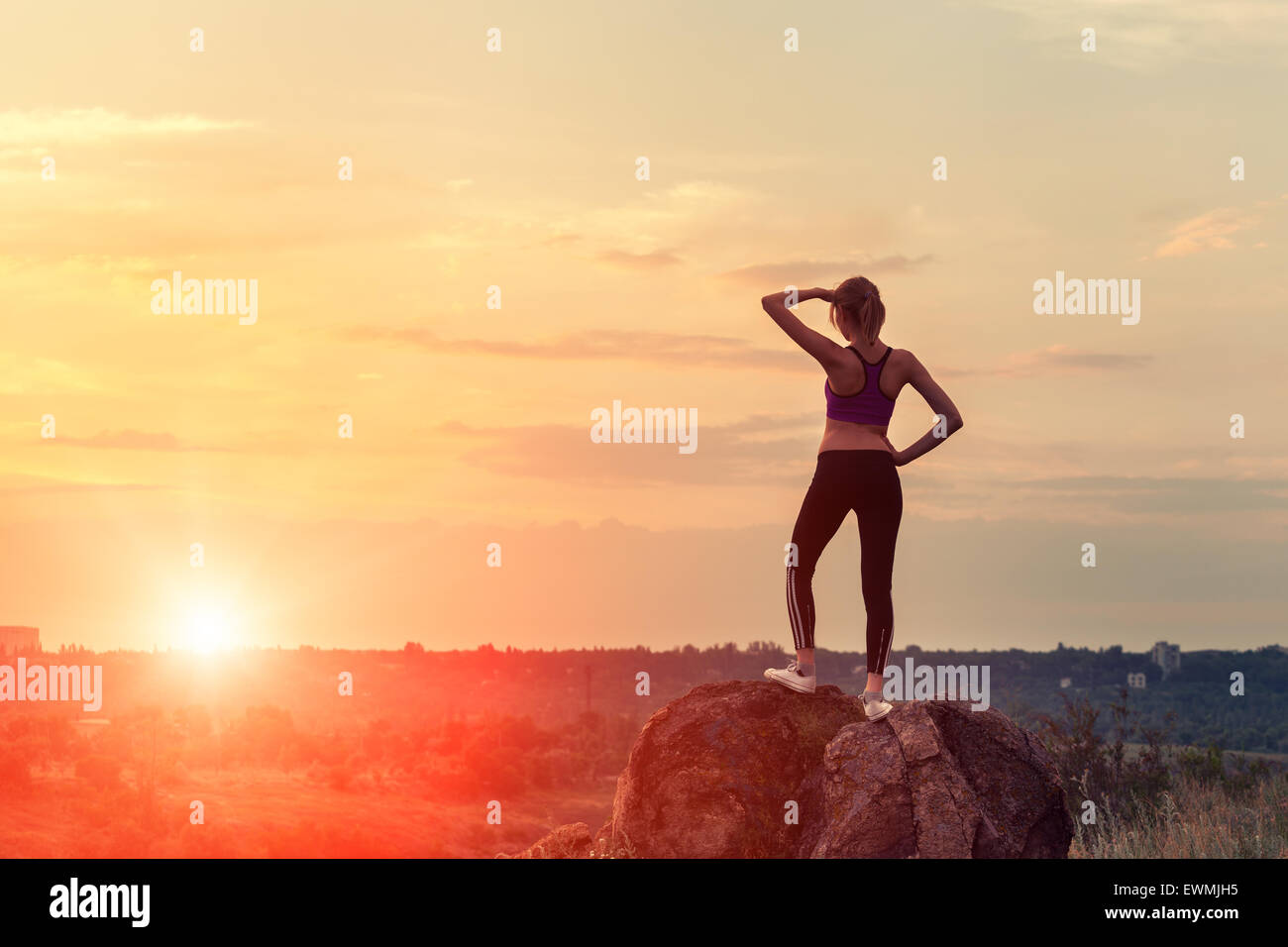 Junge sportliche Frau mit Armen hob bei Sonnenuntergang im Sommer Stockfoto