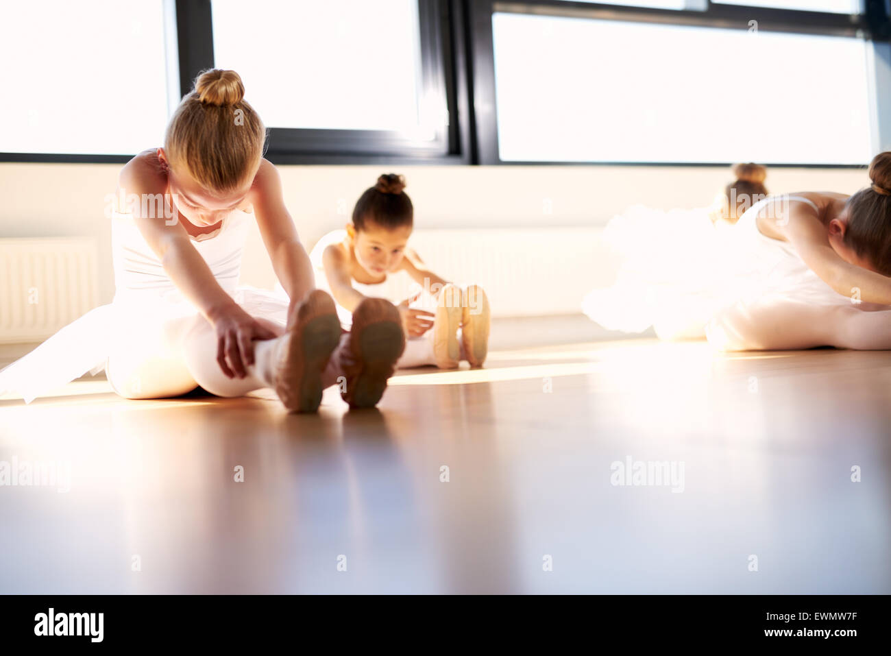Wenig Ballett Mädchen tun einen sitzen und erreichen Aufwärmübung für Body Stretching in the Studio, vor ihrer Tanz-Probe Stockfoto