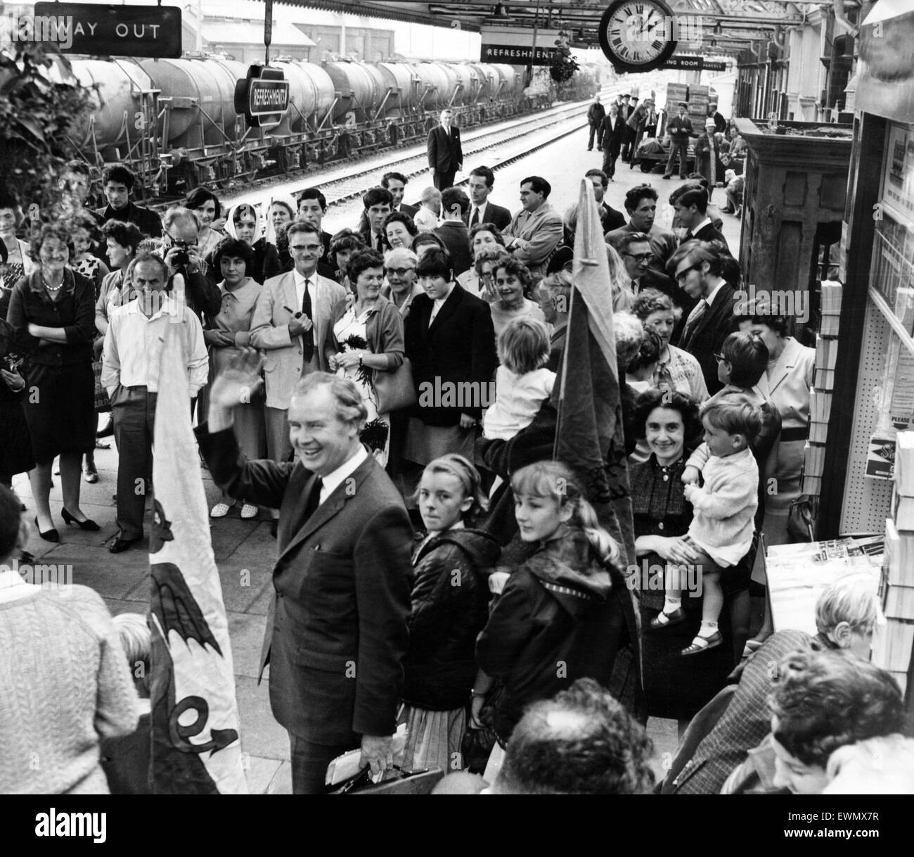 Gwynfor Evans ist einen mitreißenden senden von Camarthen Bahnhof auf dem Weg zu seinen Sitz im House Of Commons abgegeben. Stolzer Unterstützer tragen den walisischen Drachen und warten, bis ihm winken ab. 20. Juli 1966. Stockfoto