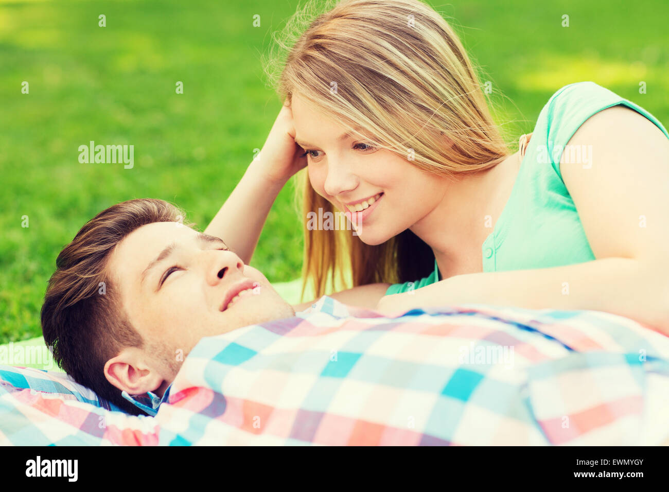 lächelnde paar liegend auf einer Decke im park Stockfoto