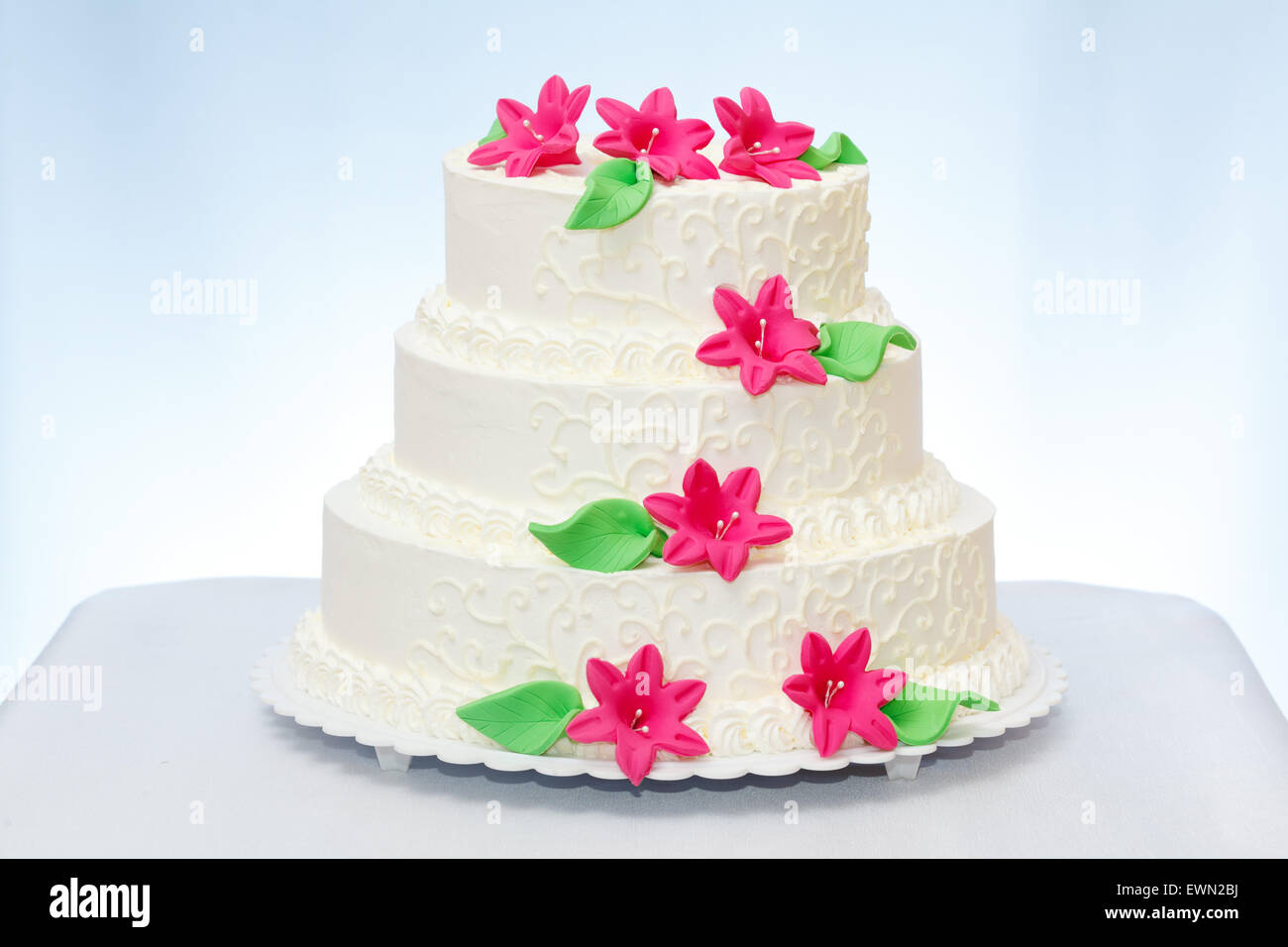 Dreistöckige weisse Hochzeitstorte mit rosa Marzipan Blumendekoration Stockfoto