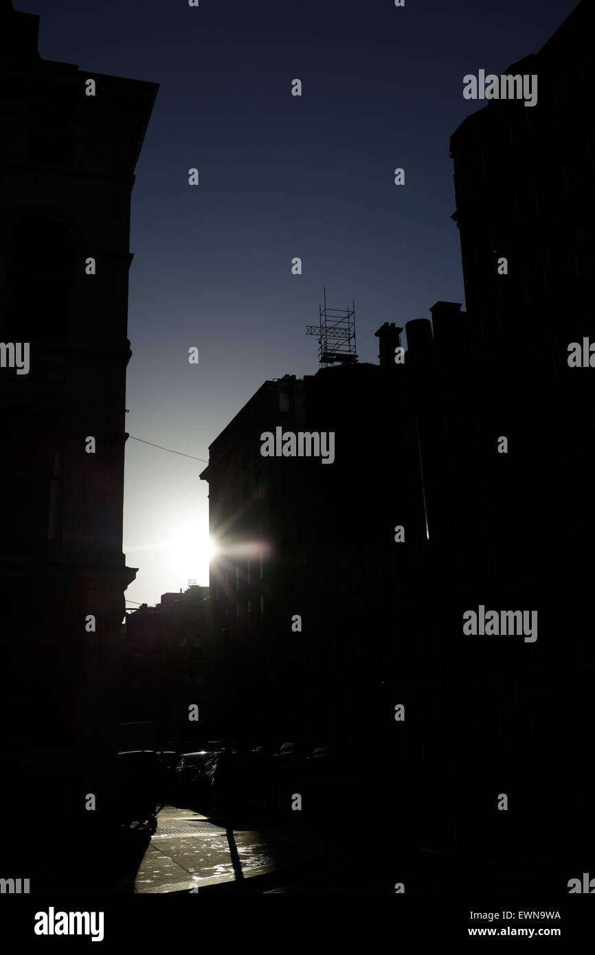 Die Sonne scheint um die Ecke eines Gebäudes an einer Stadtstraße, Großbritannien Stockfoto