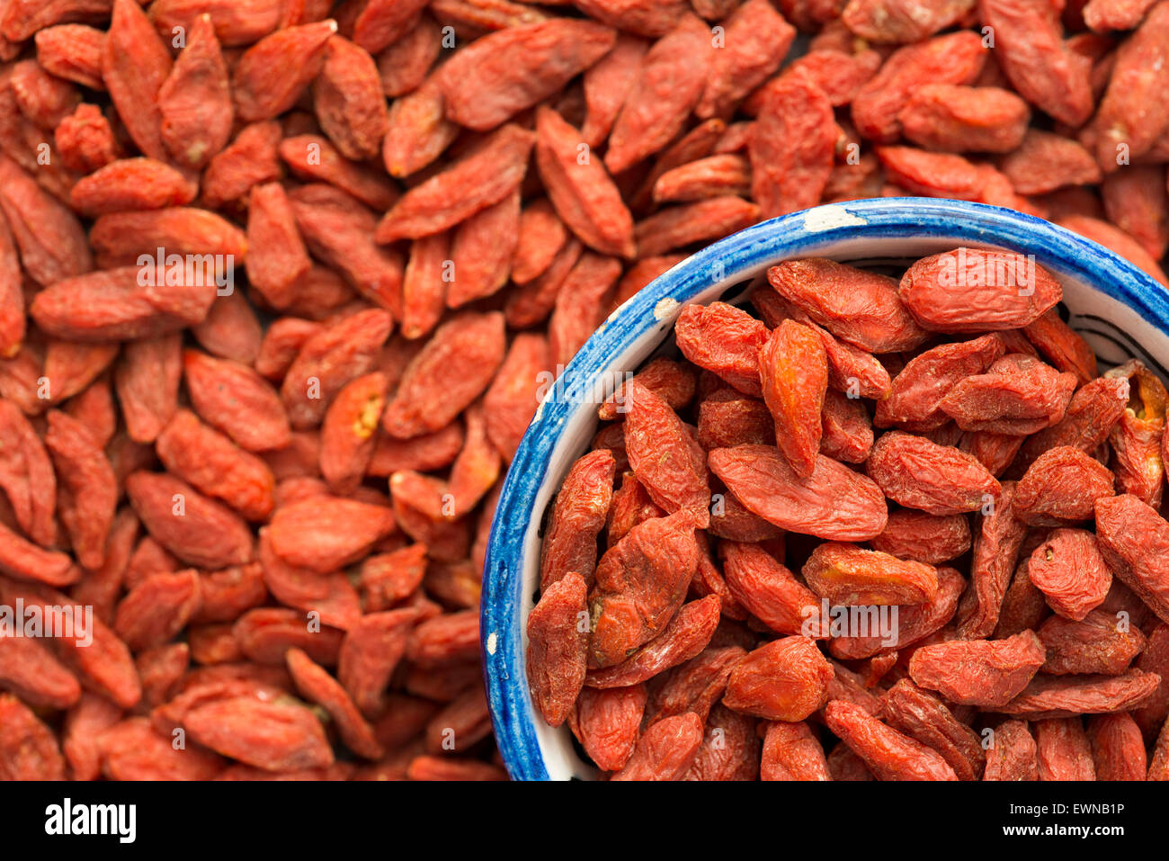 getrocknete Goji-Beeren-Hintergrund mit Fokus auf Fragment des blauen gefüllten Tasse Stockfoto