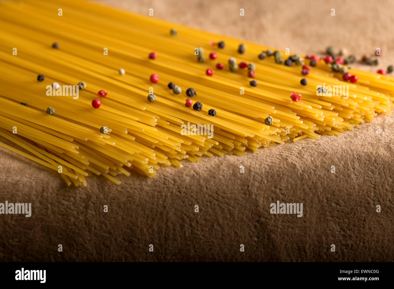 Rohe Spagetti mit Pfefferkörnern auf braunem Hintergrund Stockfoto