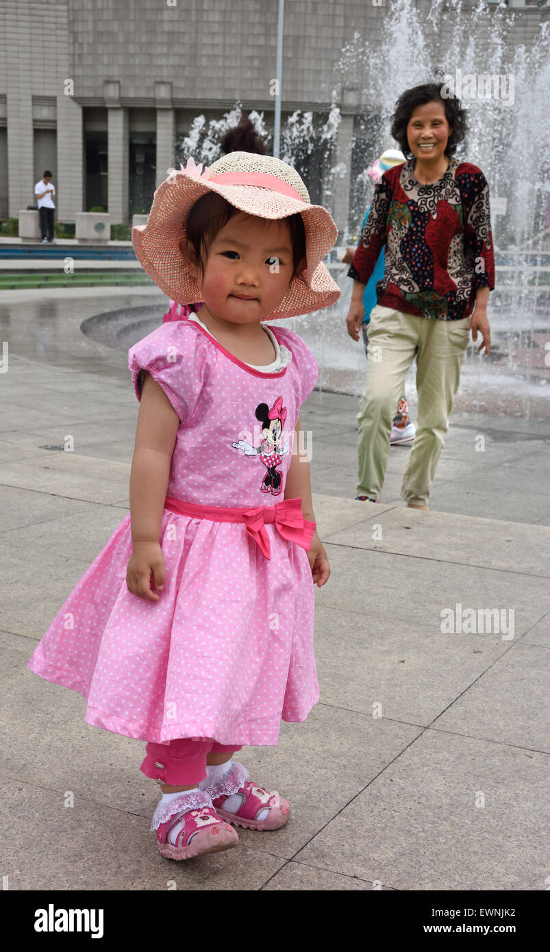 Kleines Mädchen mit rosa Kleid und Hut Brunnen mit Menschen und Kindern auf Peoples Square städtische Regierung Gebäude Gemeinde in Shanghai Skyline Stadt Stockfoto
