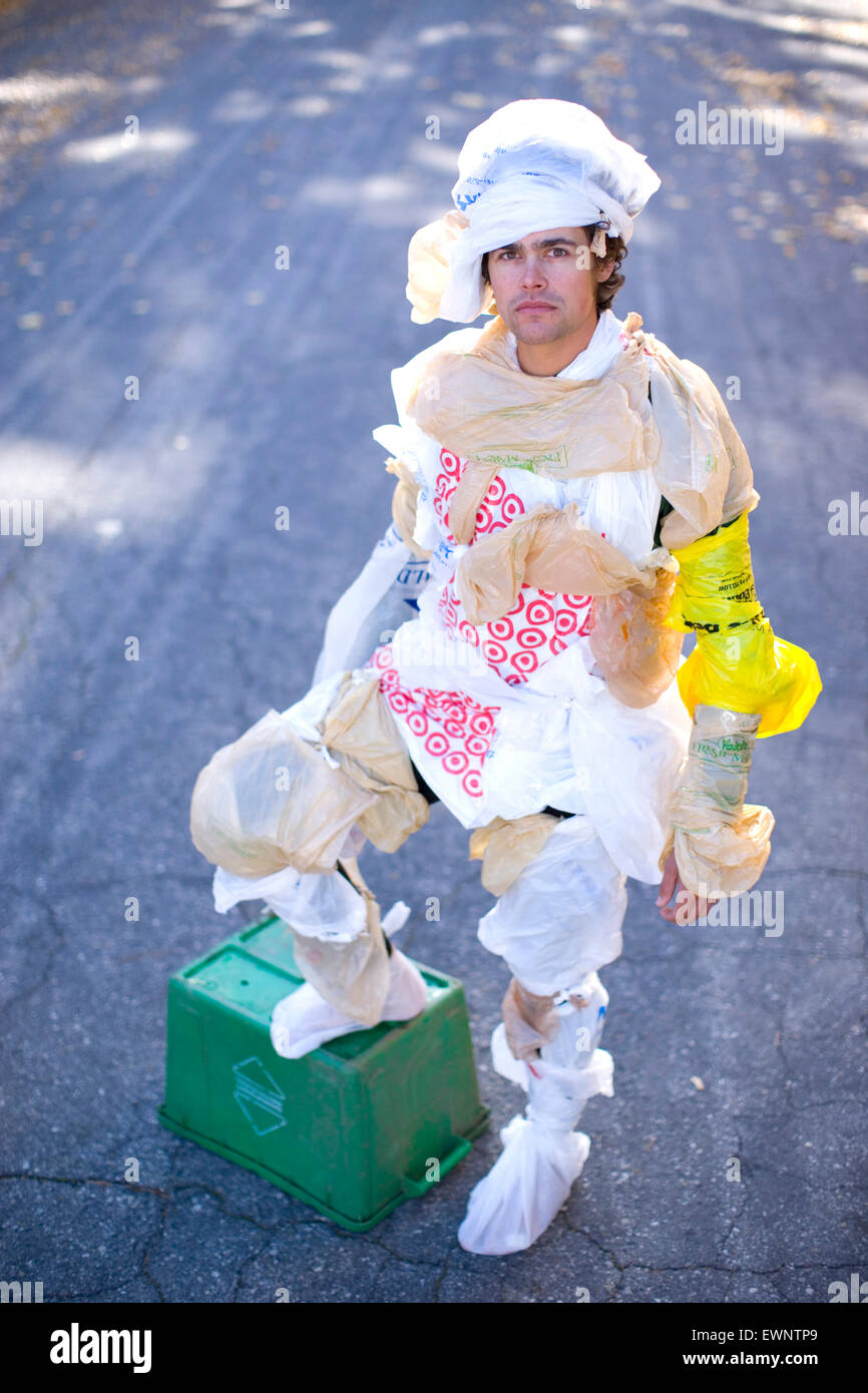Porträt von Erwachsenen Mann gekleidet in Plastiktüten mit einem Bein auf einen Papierkorb Stockfoto