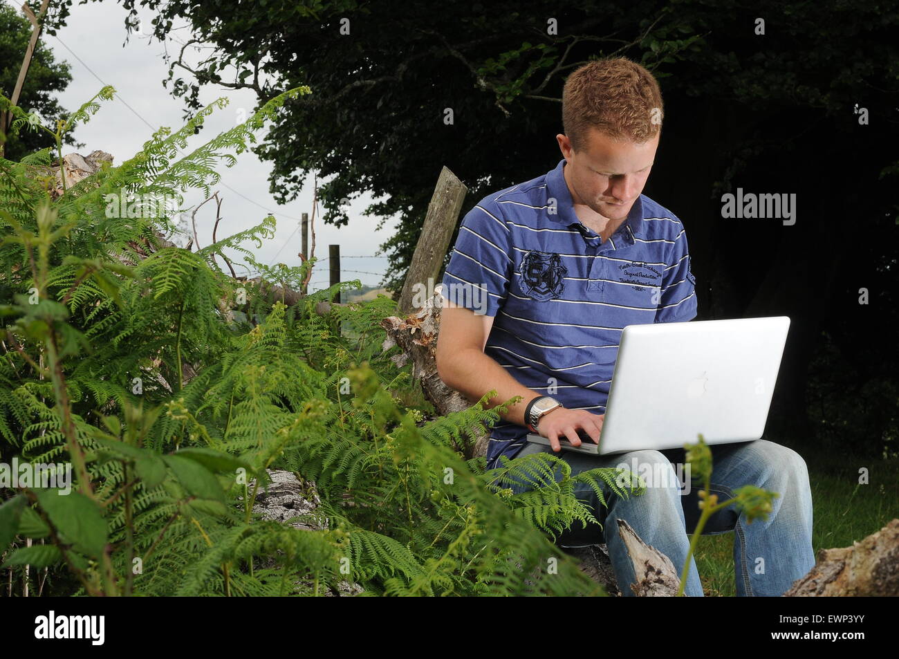 Ein Mann nutzt eine Breitband-Internetverbindung im Freien in einer ländlichen Umgebung. Stockfoto