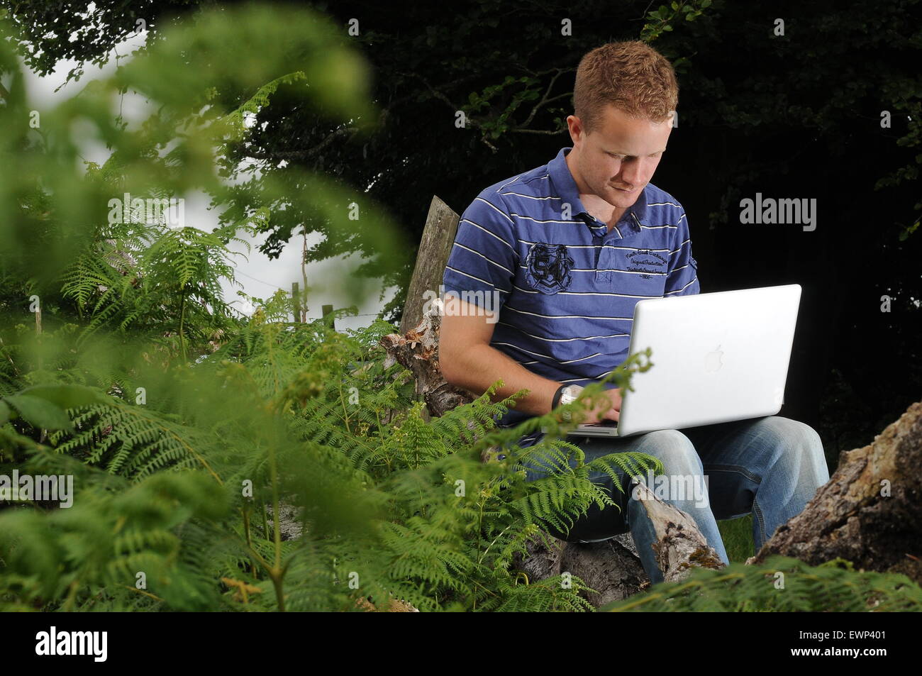 Ein Mann nutzt eine Breitband-Internetverbindung im Freien in einer ländlichen Umgebung. Stockfoto